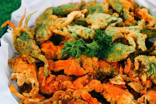 Portrait of Crispy baby Crab with balado flavour, served in a small basket with a round wooden placemat on a green floor, small fish for snacks that taste crunchy and delicious.