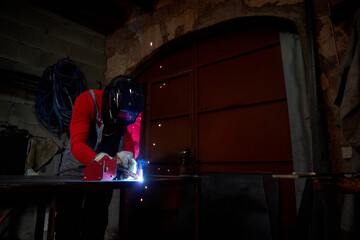 Man welding metal table in workshop