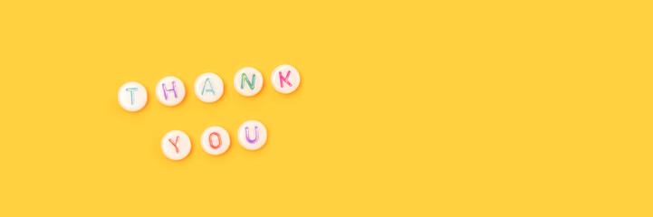 Thank you. Banner with quote made of beads with letters on a yellow background.
