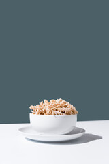 Espirales de pasta integral en un bol sobre fondo verde