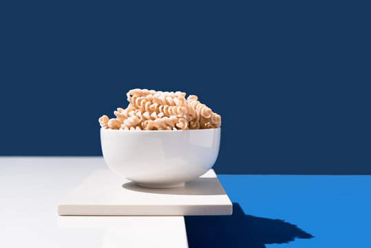 Espirales de pasta integral en un bol sobre fondo azul