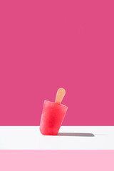 Polo de helado de fresa. Palo de helado rojo en pie sobre fondo rosa. Concepto de verano	