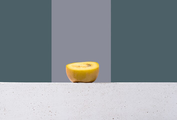 Kiwi amarillo sobre un soporte blanco y fondo gris