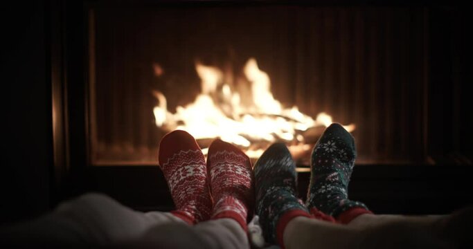 Feet in bright Christmas socks dance against the backdrop of fire in the fireplace
