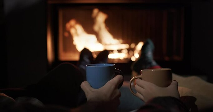 A man and a woman are sitting by the fireplace, drinking tea. Close-up shot