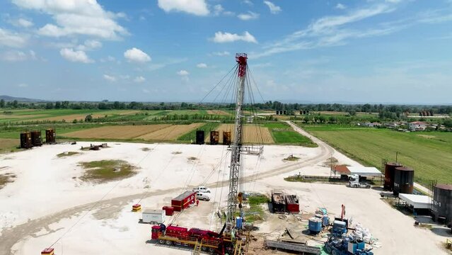 Oil well with drilling equipment in an industrial land surrounded by farming fields