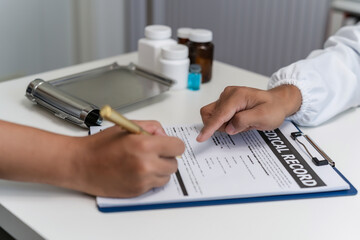 Close-up of a professional doctor and a patient signing a medical insurance policy. doctor notes healthcare paperwork