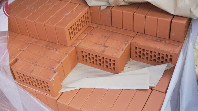 Red brick. Construction of a brick building. silica product. Pallet, packing of bricks. The bricklayer builds the walls of the house. Partitions, walls in the building. cement mortar.