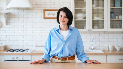 Woman standing near dining table on kitchen background