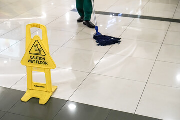 Yellow caution sign saying wet floor prevent people from falling on surface. Warning of slippery...