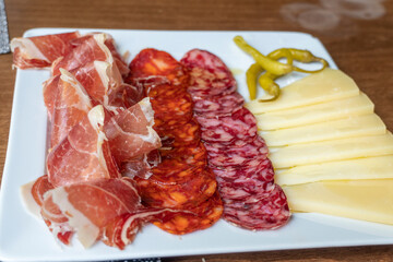 Plate with sausages chorizo salchichon manchego cheese and serrano ham Spanish appetizer