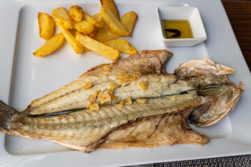 Fried sea bass with french fries on plate Spain
