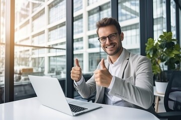 Fototapeta na wymiar happy businessman in eyeglasses showing thumbs up while working with laptop in office