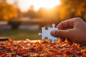 Hand holding jigsaw puzzle piece in autumn park. Business solutions concept