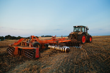 A tractor with a large disc harrow for tillage. Farmer work concept.