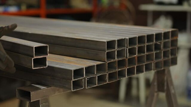 Welder or blacksmith taking metal iron square pipe profiles from warehouse for project. concept: manual work, blacksmith, industry, welder