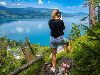 A girl shoots the Attersee lake from the Klettersteig mountain, Austria. Lake Attersee from the top of the Klettersteig. Salzburgerland, Austria.