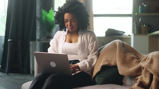 Pretty young woman freelancer working online typing browsing on laptop laying on sofa at late evening indoors Positive female enjoying great working day at cozy home - Powered by Adobe