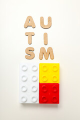 The word autism in wooden letters on a light background with blockss. World autism day concept