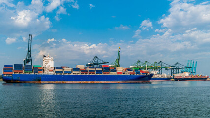 Fototapeta premium Antwerp, Belgium, view of harbor cranes and container ships in the largest dock of the port of Antwerp. Huge container vessel in the harbor with containers
