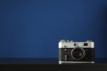 Vintage camera on wooden table on blue background, space for text