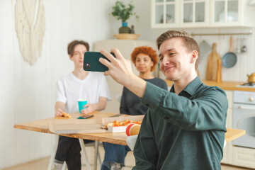 Cheers Funky mood. Happy group of friends make selfie. Man taking photo of friends at party. Group of multiracial young people taking photo on phone. Young people enjoy their company smile have fun