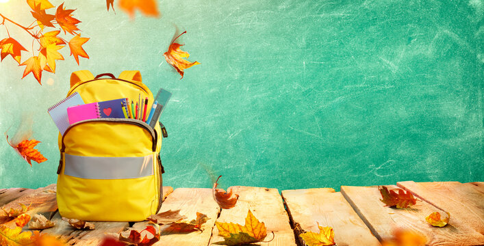 Schoolbag On Table With Stationary And Leaves - Backpack For Back To School Concept