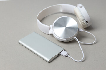 Silver powerbank and headphones on gray background