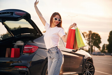 Excited for the sales. Beautiful woman in casual clothes is holding shopping bags, outdoors