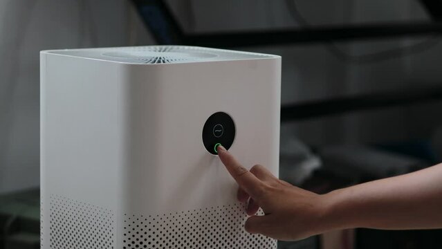 Women touch screen Air purifier in living room for select health mode protect PM 2.5 dust. Human Health and Technology concept. Fresh air.