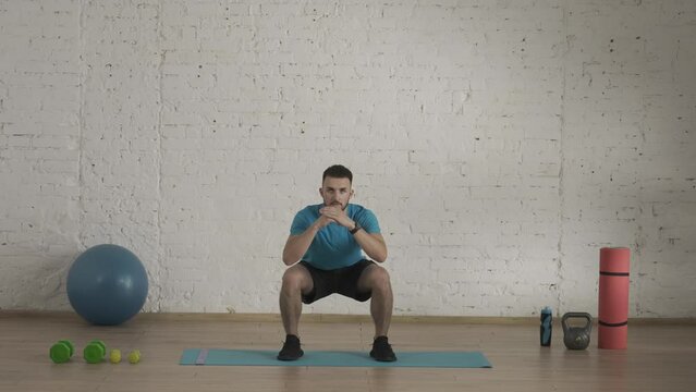 Man fitness coach in sportswear doing squats exercise for online class at the home studio. HDR BT2020 HLG Material.