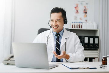 Attractive male doctor talking while explaining medical treatment to patient through a video call with laptop in office