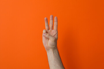 Female hand showing three fingers on a orange background
