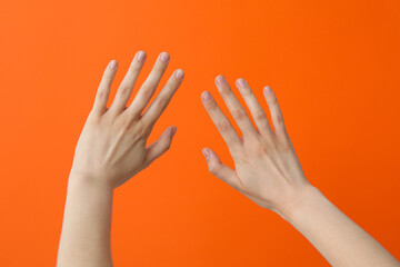 Two female hands with spread fingers on an orange background