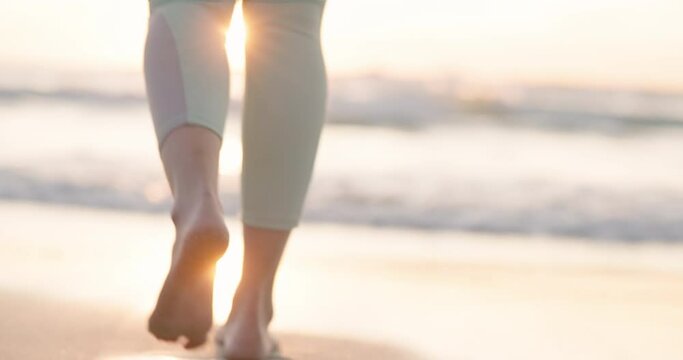 Beach, sunset and legs of person walking, travel and relax with ocean water, sand and foot steps on holiday break. Nature wellness, sea waves and barefoot feet of closeup tourist for outdoor freedom