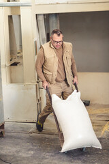 worker transporting a heavy sack with a hand truck