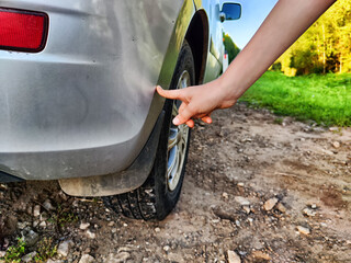 The child points at a scratch on the car. The child's hand scratches and damages the vehicle. Accident, damage, breakdown, repair, vehicle paint - obrazy, fototapety, plakaty