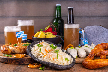  Oktoberfest munich traditional festival menu foods - bavarian sausages, pretzels, potato, sauerkraut, beer bottle and mug,  Background flyer for Oktoberfest invitation on old wooden table