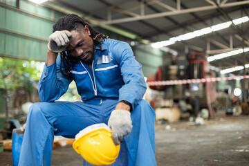Man African American worker industrial sitting resting with fatigue. Hand wipe sweat tired from work. professional worker manufacturing. employee technician tired overworked.