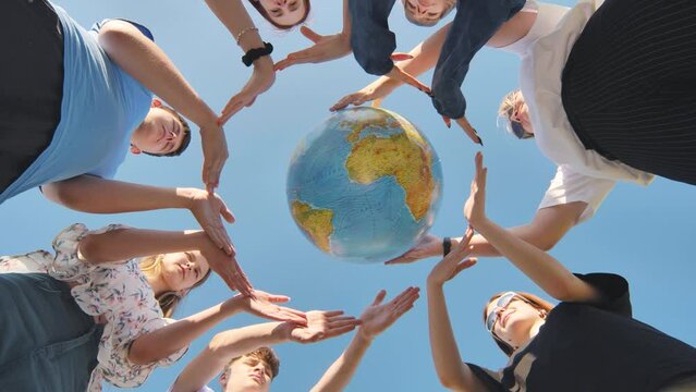 Young boys surround the globe of the world with their palms. The concept of preserving world peace.