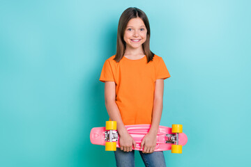 Photo of cheerful sweet girl toothy smile hands hold penny board stand empty space isolated on cyan color background