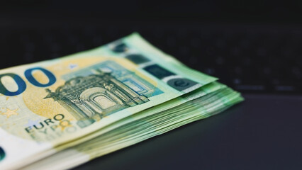 Close-up. The workplace, on which lies an open laptop, and next to it is a pile of money. Effective money management. Work from home.