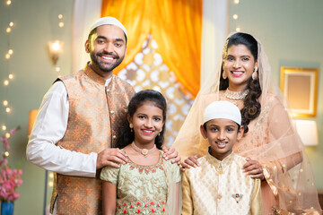 Happy smiling indian muslim parents with kids looking at camera during ramdan festival celebration...