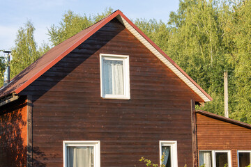 Fototapeta na wymiar A small neat wooden village house covered with dark brown impregnation