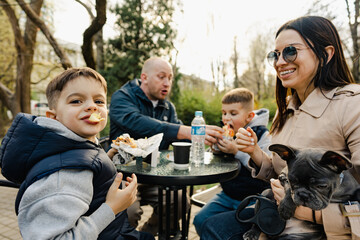 Happy family with two kids having a sancak at outdoor cafe on autumn day