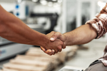 Two men shaking hands on background of workshop