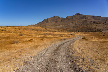 Fototapeta na wymiar Panoramic view of of mountains with a dirt road in the Gata Cape Natural Park coast. Almería, Andalucía, Spain.