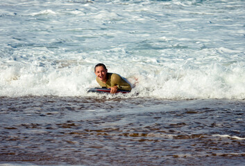 Cute young woman with her bodyboard in swimsuit surfing the waves