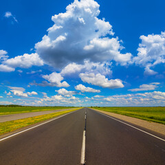 long asphalt road under blue cloudy sky