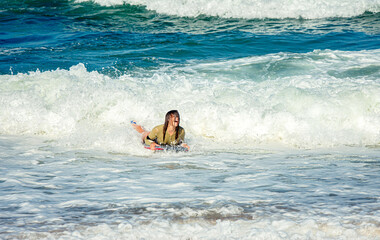 Cute young woman with her bodyboard in swimsuit surfing the waves